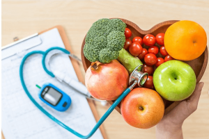 A person holds a heart-shaped bowl filled with an assortment of colorful fruits and vegetables.